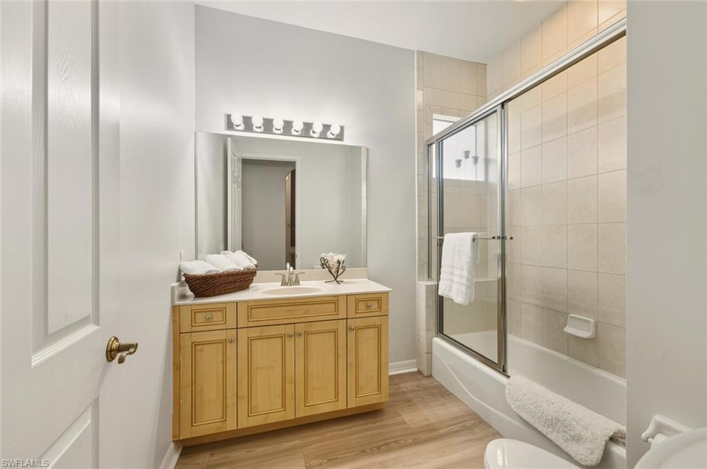 10800 Fieldfair Drive Naples, FL 34119 - Photo 27 of 47 Full bathroom featuring vanity, bath / shower combo with glass door, and light wood-style floors