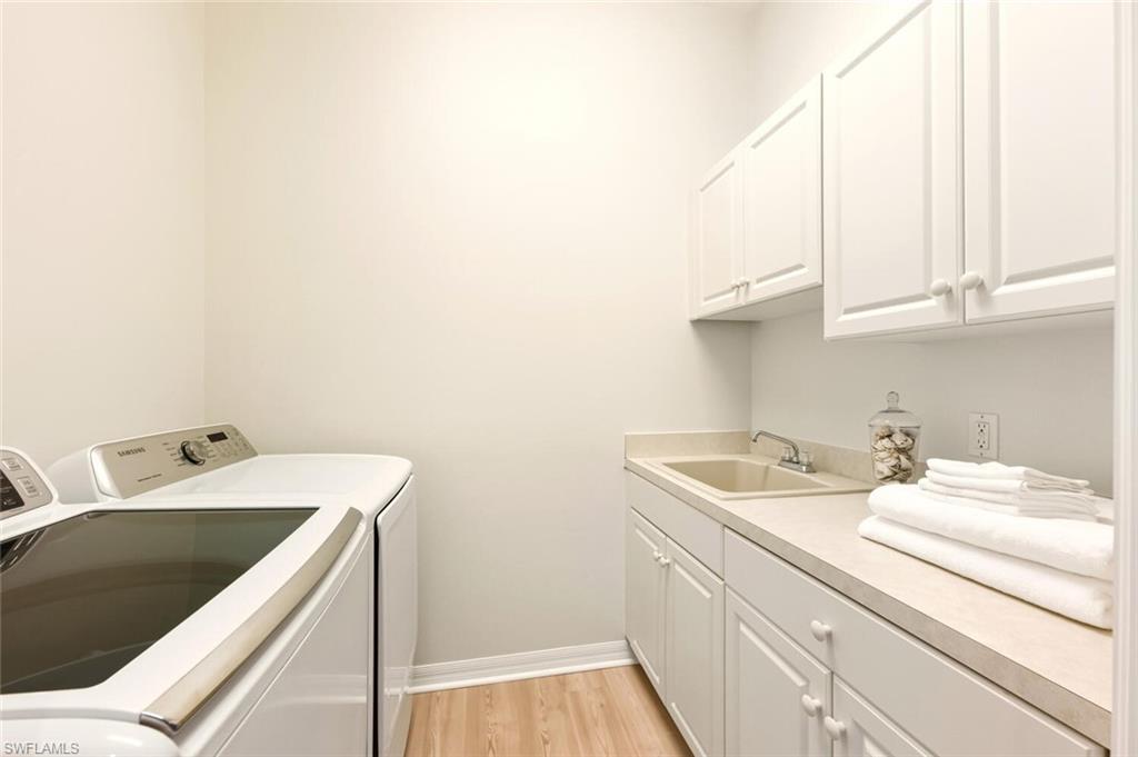 10800 Fieldfair Drive Naples, FL 34119 - Photo 36 of 47 Washroom with cabinet space, light wood-type flooring, and washing machine and clothes dryer