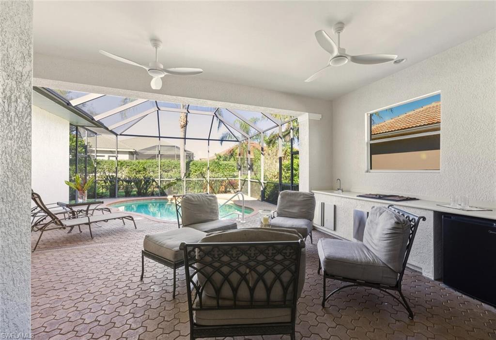 10800 Fieldfair Drive Naples, FL 34119 - Photo 37 of 47 View of patio featuring a sunroom, ceiling fan, an outdoor kitchen, and glass enclosure