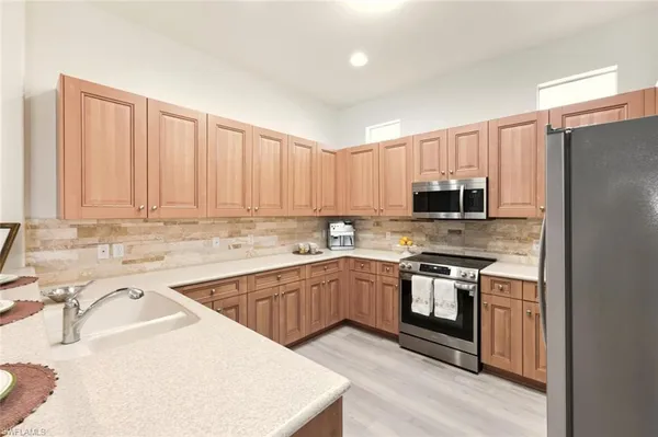 a kitchen with a refrigerator a stove a sink and chairs