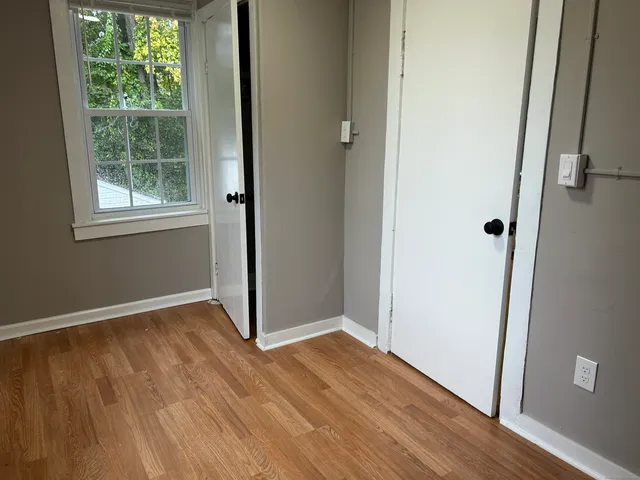 an empty room with wooden floor and windows