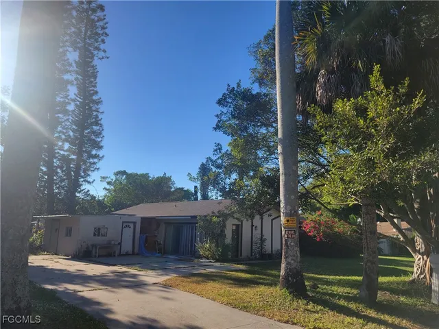 a view of a house with a small yard and a large tree
