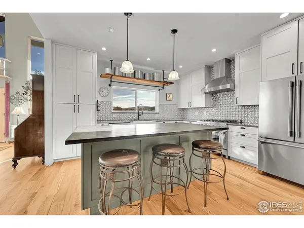 a kitchen with stainless steel appliances granite countertop a sink a stove a refrigerator and wooden floor