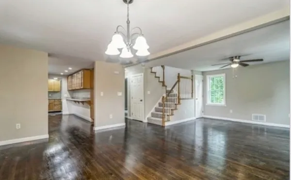 a view of a room with wooden floor chandelier and windows