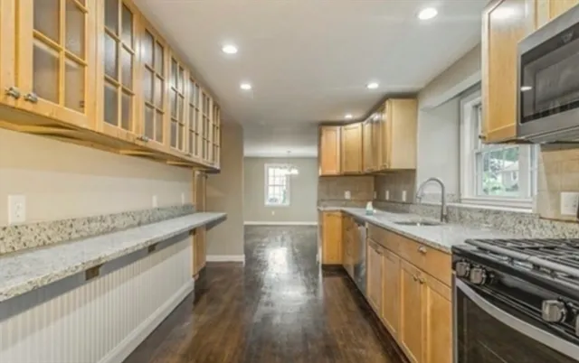 a large kitchen with stainless steel appliances granite countertop a lot of counter space and wooden floor