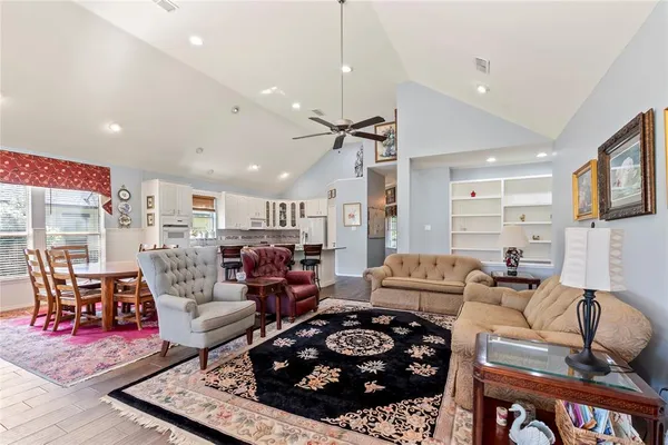 a living room with furniture a rug kitchen view and a chandelier