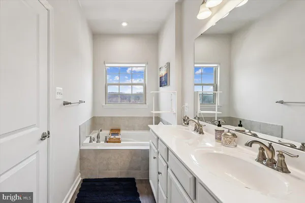 a bathroom with a tub sink and mirror