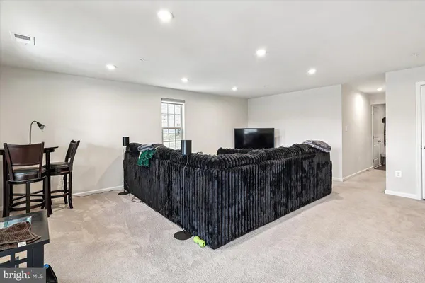 a living room with furniture a flat screen tv and a refrigerator
