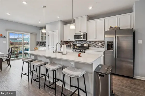 a kitchen with stainless steel appliances a table chairs refrigerator and microwave