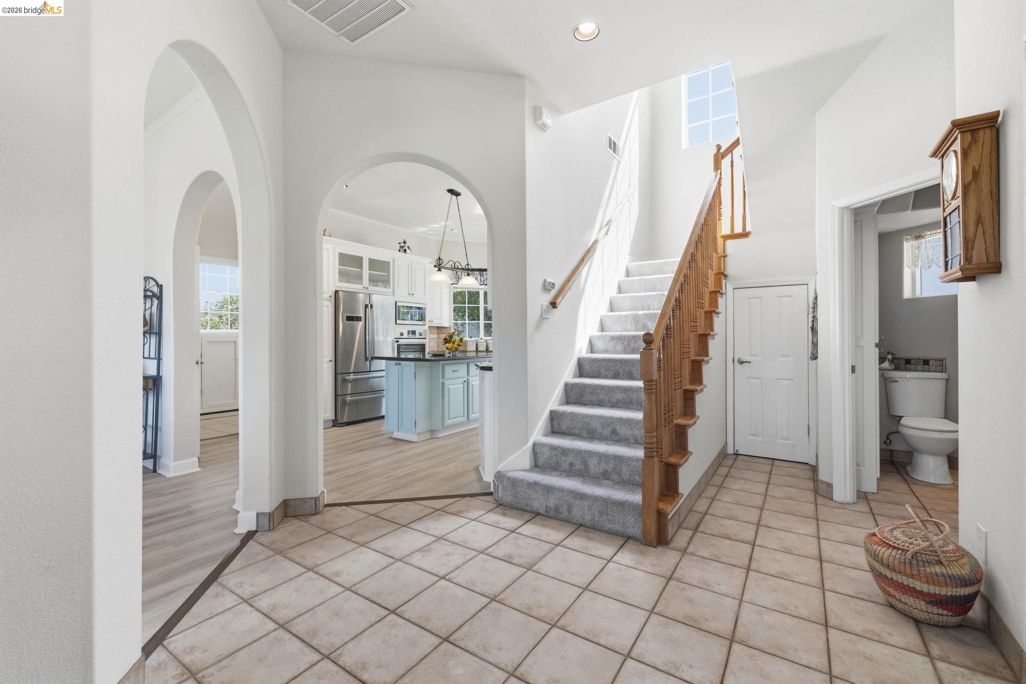 6242 Bluff View Road Copperopolis, CA 95228 - Photo 13 of 59 Foyer featuring tile flooring, arched doorways, staircase with wood balustrade and new carpet