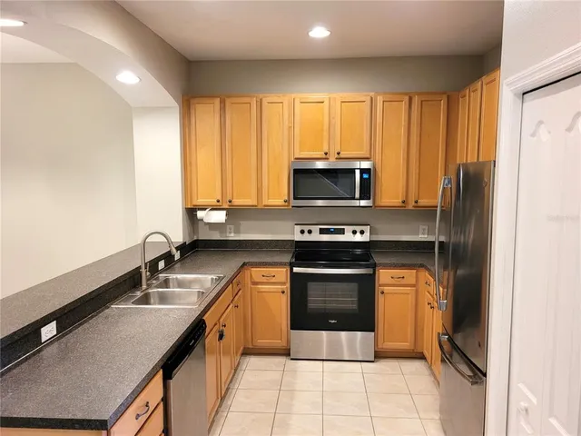 a kitchen with stainless steel appliances granite countertop a sink stove and refrigerator