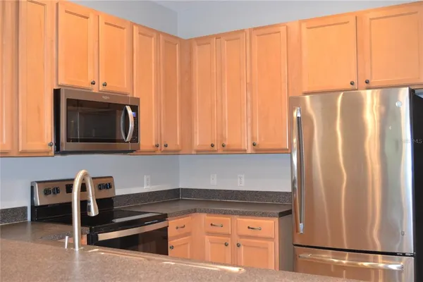 a kitchen with granite countertop a refrigerator stove and cabinets