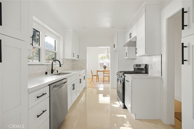 a kitchen with sink a stove and white cabinets