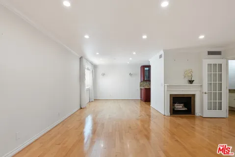 a view of an empty room with wooden floor fireplace and a window