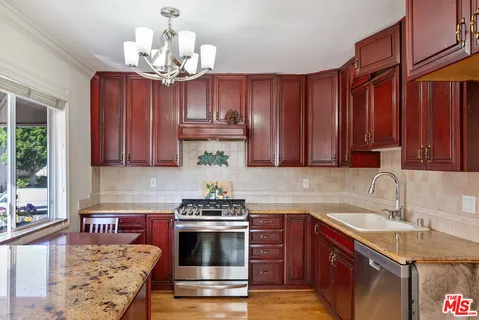 a kitchen with stainless steel appliances granite countertop a sink stove and cabinets