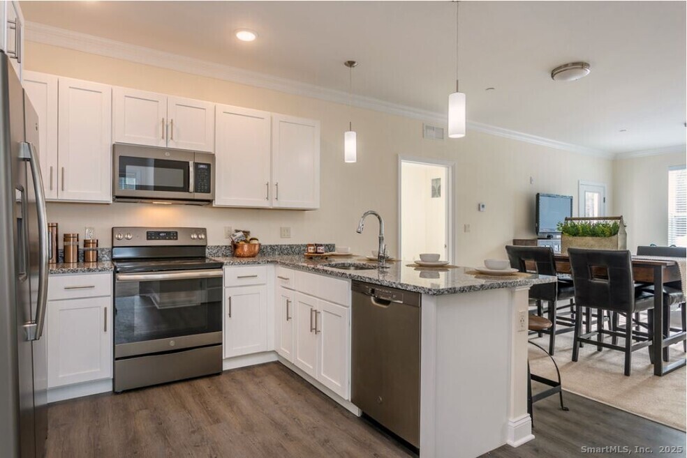 a kitchen with stainless steel appliances kitchen island granite countertop a stove top oven a sink dishwasher a dining table and chairs