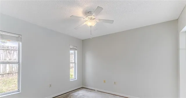 an empty room with windows and fan