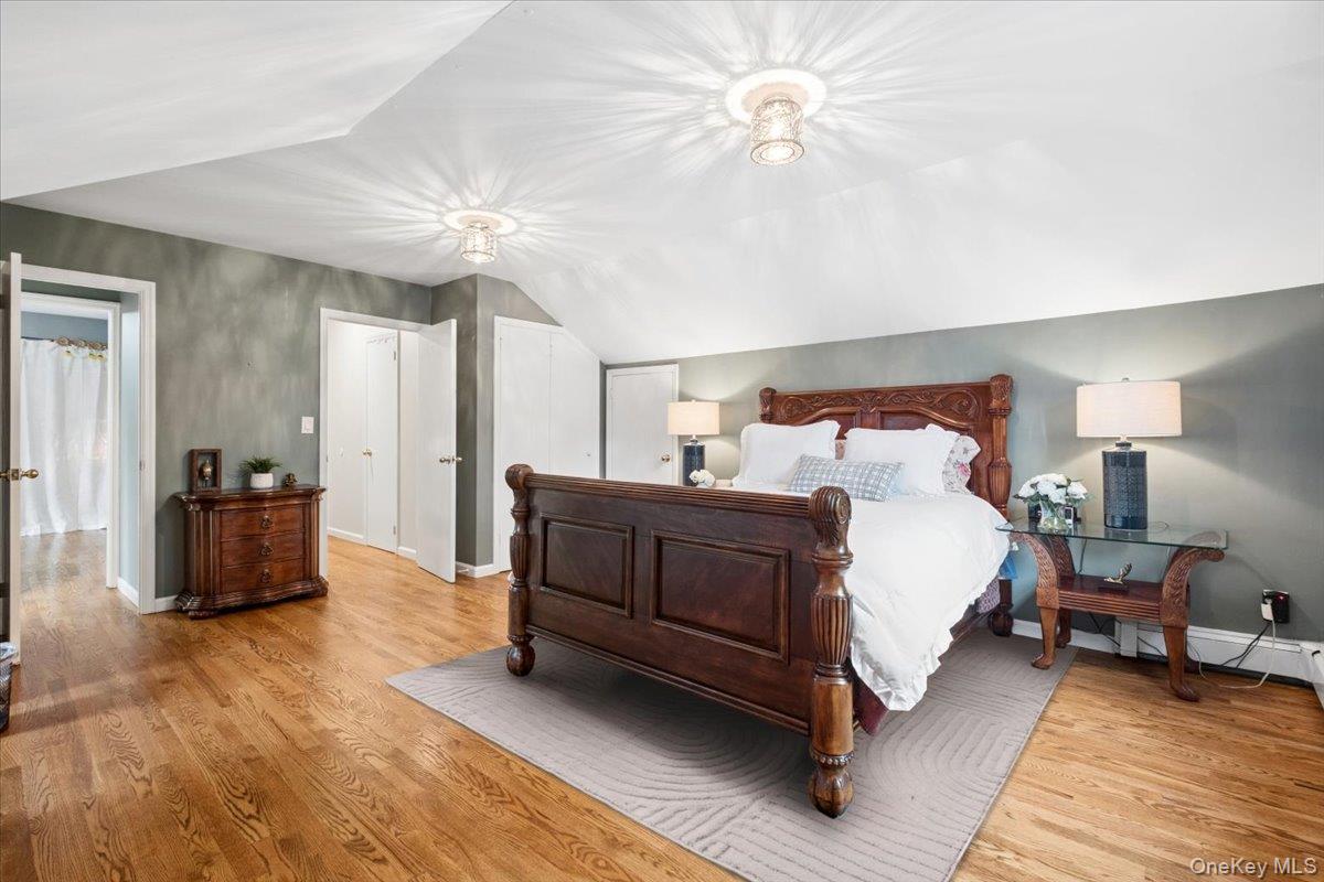 30 Stonehouse Road Scarsdale, NY 10583 - Photo 16 of 24 Hardwood flooring extends throughout this primary bedroom, featuring an angled ceiling and two walk-in-closets.
