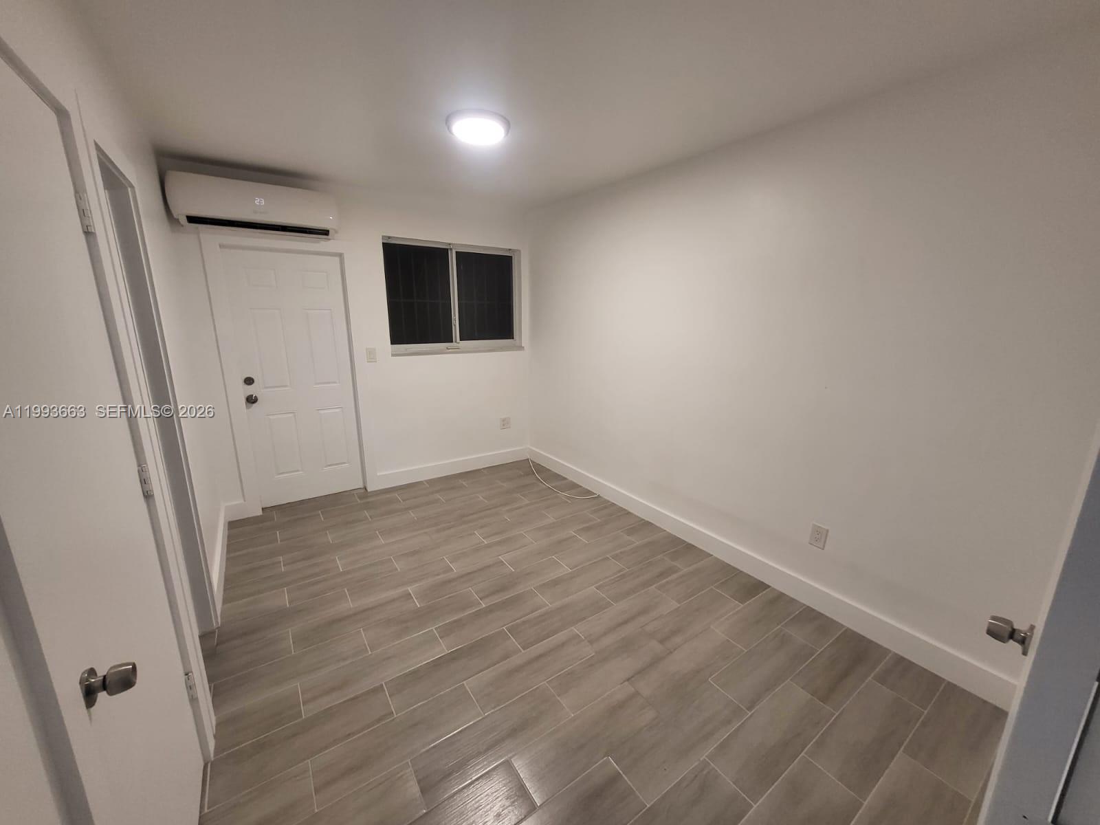 599 Northwest 33rd Street Miami, FL 33127 - Photo 6 of 8 an empty room with wooden floor and windows