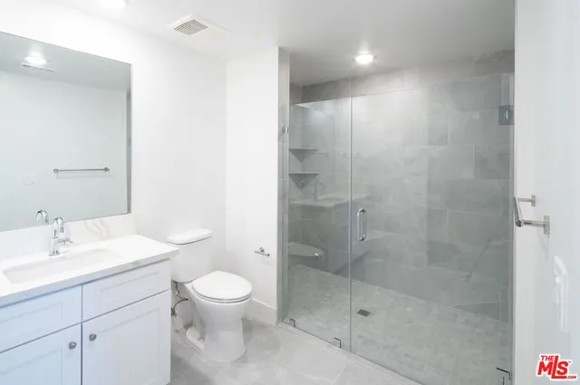 a bathroom with a shower sink vanity mirror and toilet