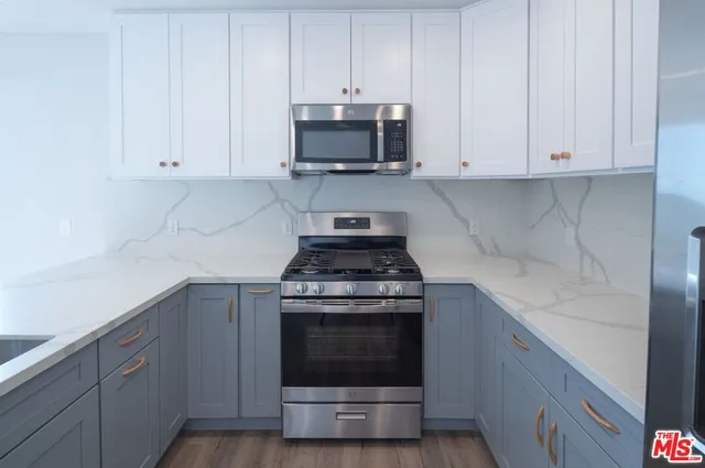 a kitchen with granite countertop white cabinets and stainless steel appliances