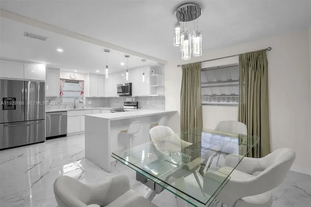 a kitchen with stainless steel appliances kitchen island granite countertop a refrigerator a stove a sink dishwasher a dining table and chairs with wooden floor