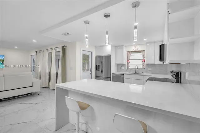 a large kitchen with kitchen island a large counter top stainless steel appliances and cabinets