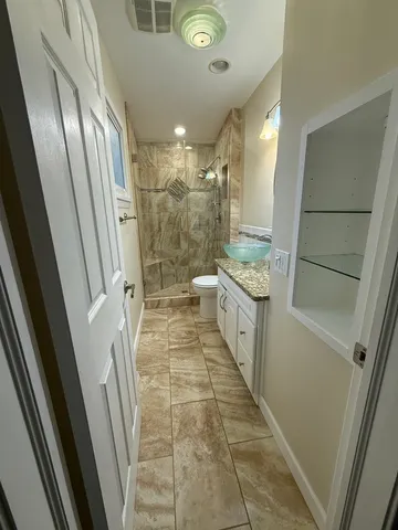 a bathroom with a granite countertop sink toilet and shower
