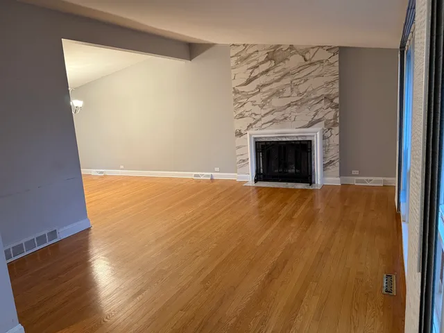 a view of empty room with wooden floor and a fireplace