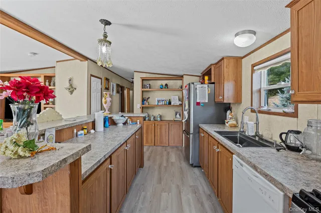 a kitchen with stainless steel appliances granite countertop a refrigerator a sink dishwasher a stove and a dining table with wooden floor