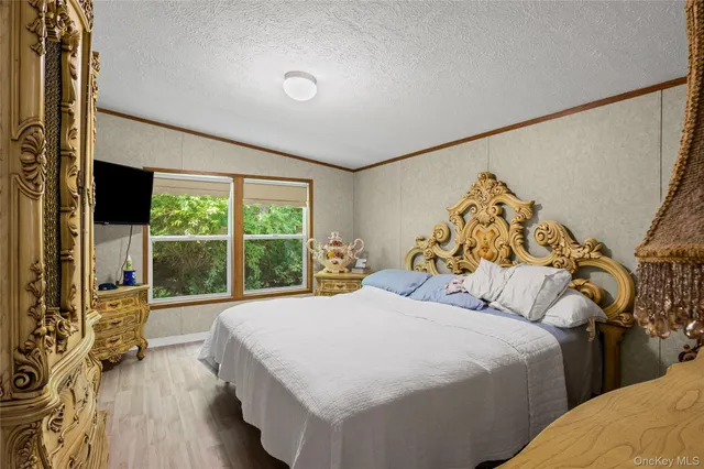 a bedroom with a bed and a flat tv screen on dresser
