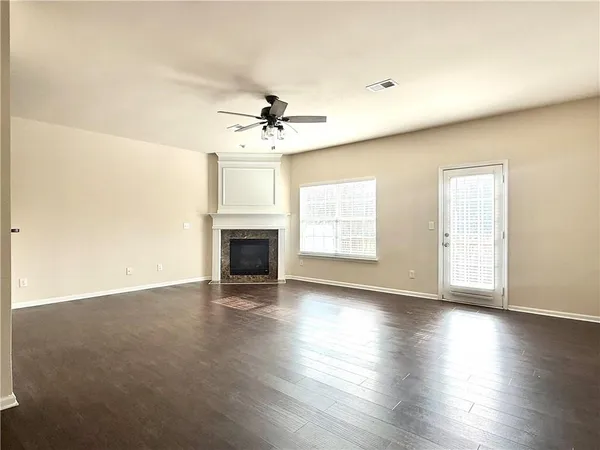 an empty room with wooden floor fireplace and windows