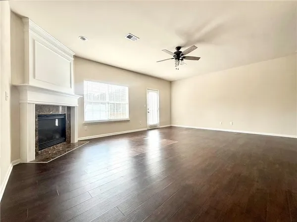 an empty room with windows fireplace and a kitchen view