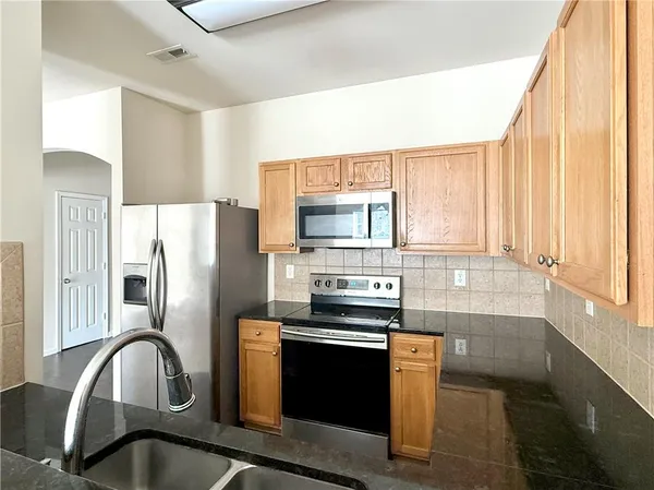 a kitchen with granite countertop a refrigerator stove and sink
