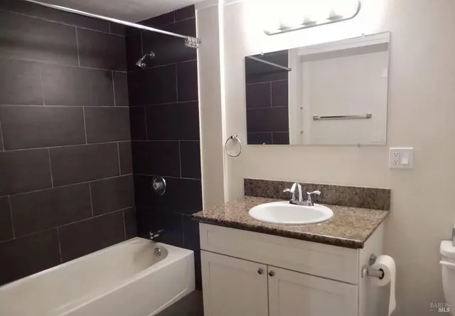 a bathroom with a granite countertop sink a mirror and a bathtub