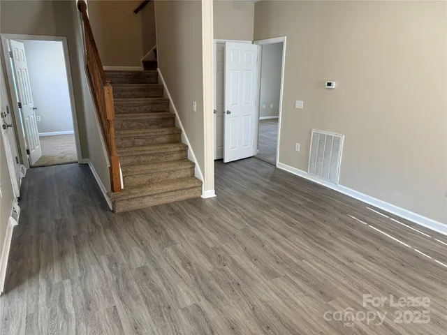 a view of a hallway with wooden floor and stairs