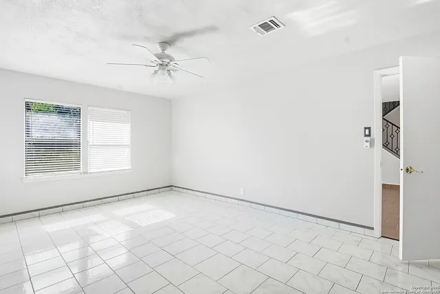 an empty room with windows and ceiling fan