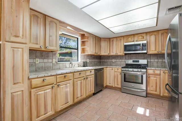 a kitchen with granite countertop a sink cabinets stainless steel appliances and a window