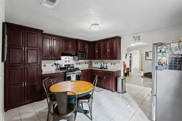 a kitchen with stainless steel appliances granite countertop a table chairs sink refrigerator and cabinets