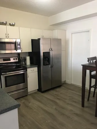 a kitchen with granite countertop a refrigerator and a stove top oven