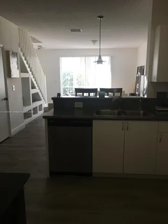 a kitchen with a sink and a wooden floor