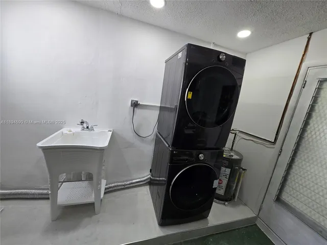 a kitchen with stainless steel appliances a sink a refrigerator a window and white cabinets