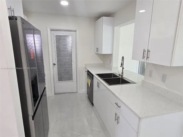 a kitchen with a refrigerator a stove and white cabinets