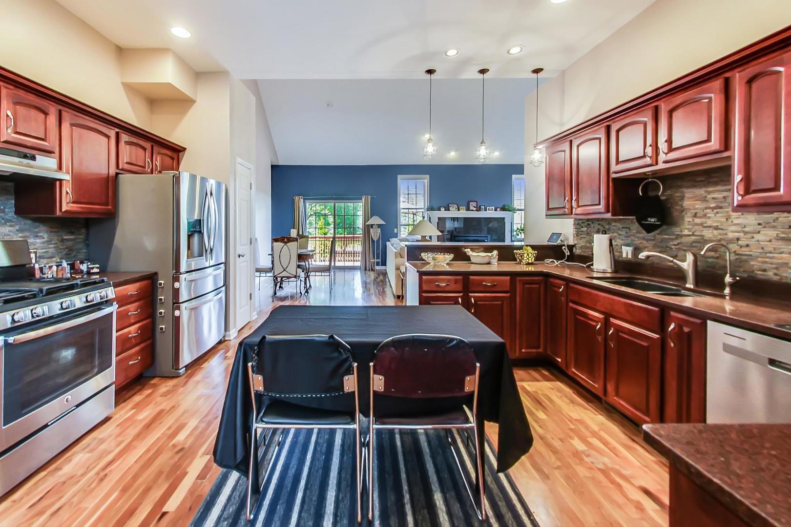 2101 Bull Ridge Drive McHenry, IL 60050 - Photo 14 of 83 a kitchen with stainless steel appliances granite countertop a refrigerator a sink dishwasher a stove and a dining table with wooden floor