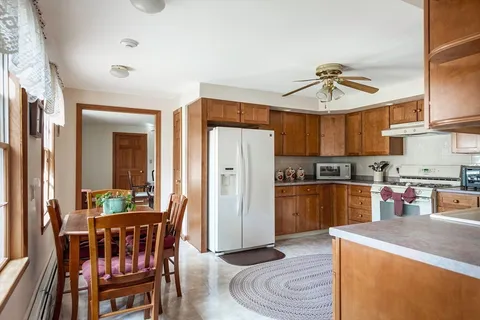 a kitchen with stainless steel appliances kitchen island granite countertop a refrigerator a stove a sink a dining table and chairs with wooden floor