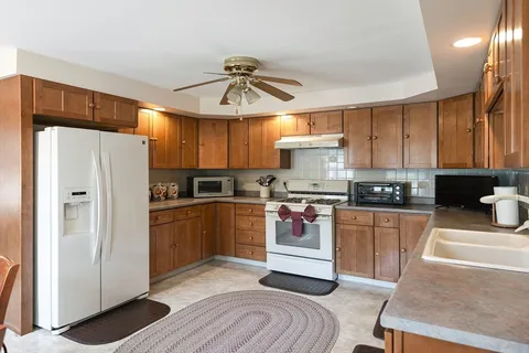 a kitchen with stainless steel appliances a refrigerator a stove a sink dishwasher and white cabinets with wooden floor