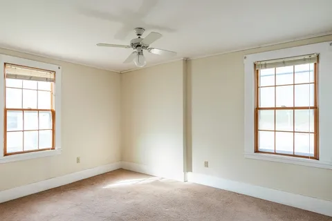 an empty room with windows and fan
