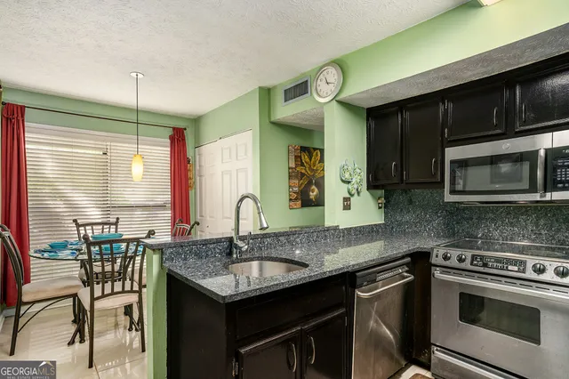 a kitchen with stainless steel appliances granite countertop a stove a sink and a microwave