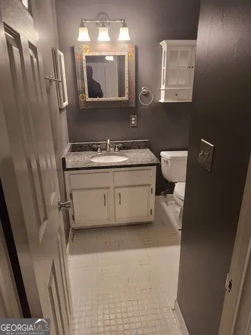 a bathroom with a granite countertop sink a mirror and a toilet
