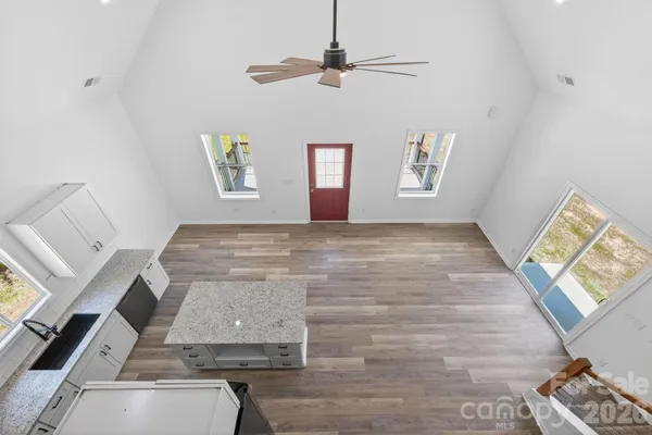 an empty room with wooden floor and ceiling fan